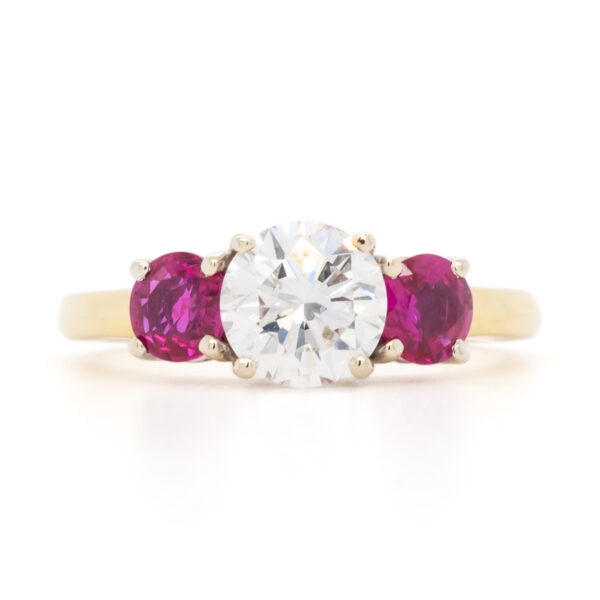 Yellow gold three-stone ring with a round brilliant diamond center flanked by two vivid red rubies, designed by Bradley D. Weber.